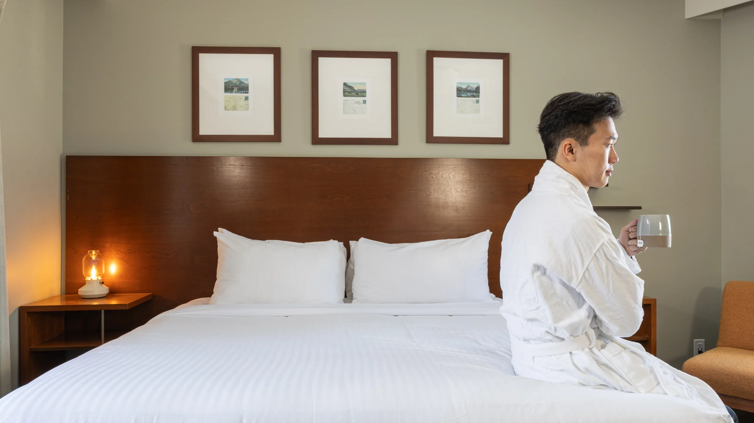 A guest sits on the King bed in the forest view room of the 3-bedroom suite
