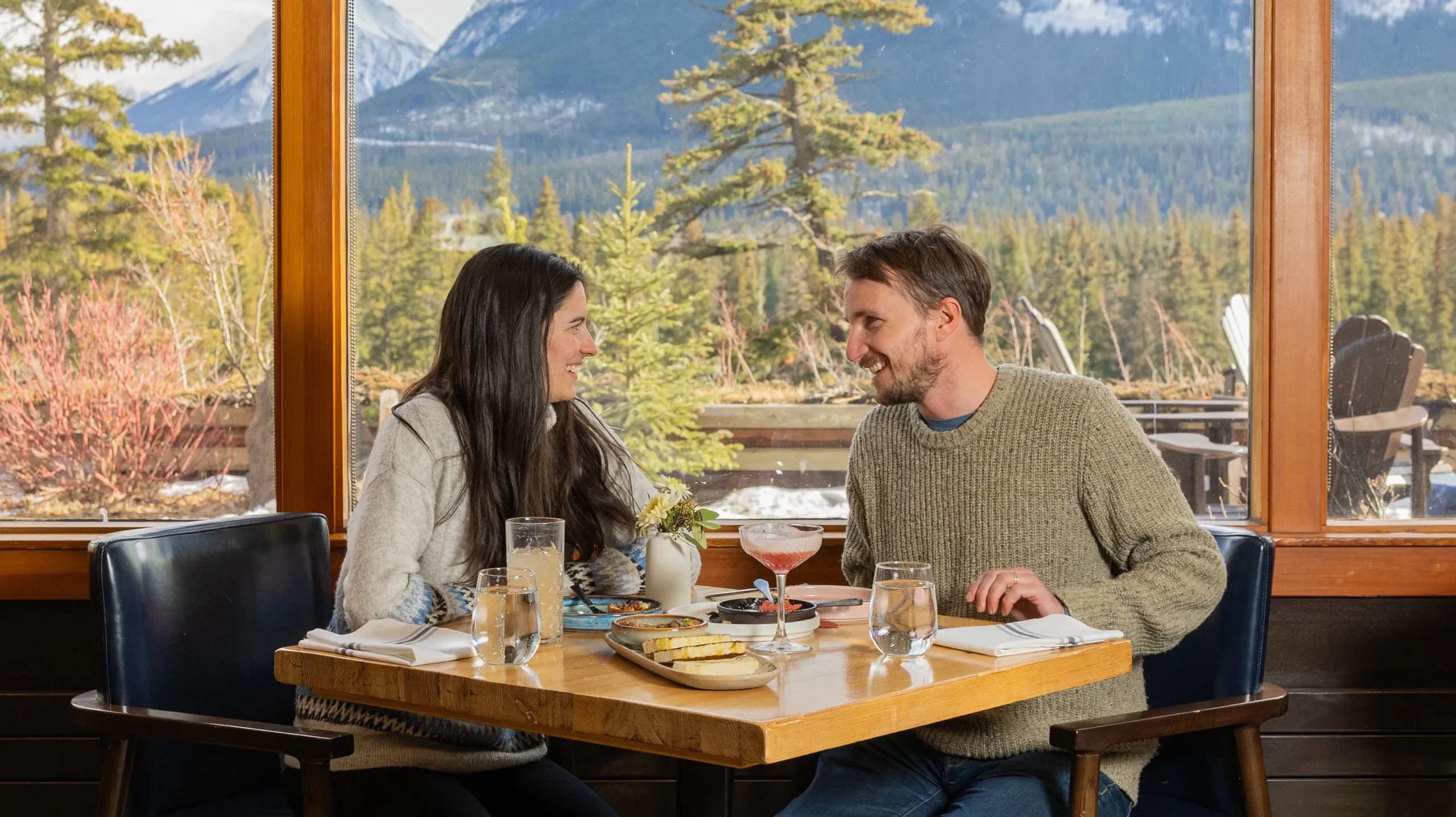 A couple enjoy breakfast at the Juniper Bistro with views over the Bow Valley behind them