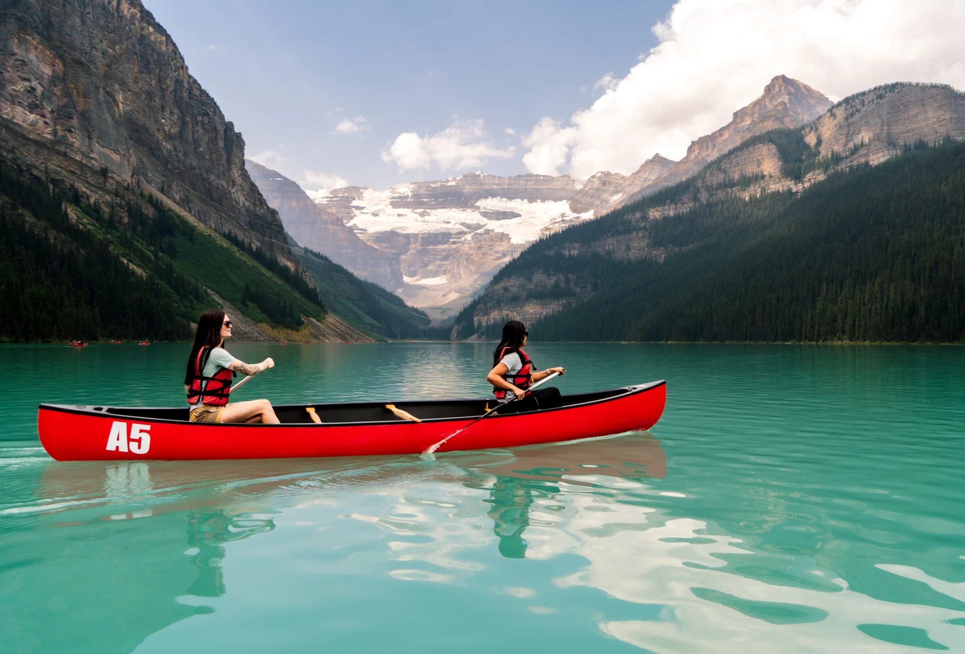 Two people paddle on the still turquoise waters of Lake Louise