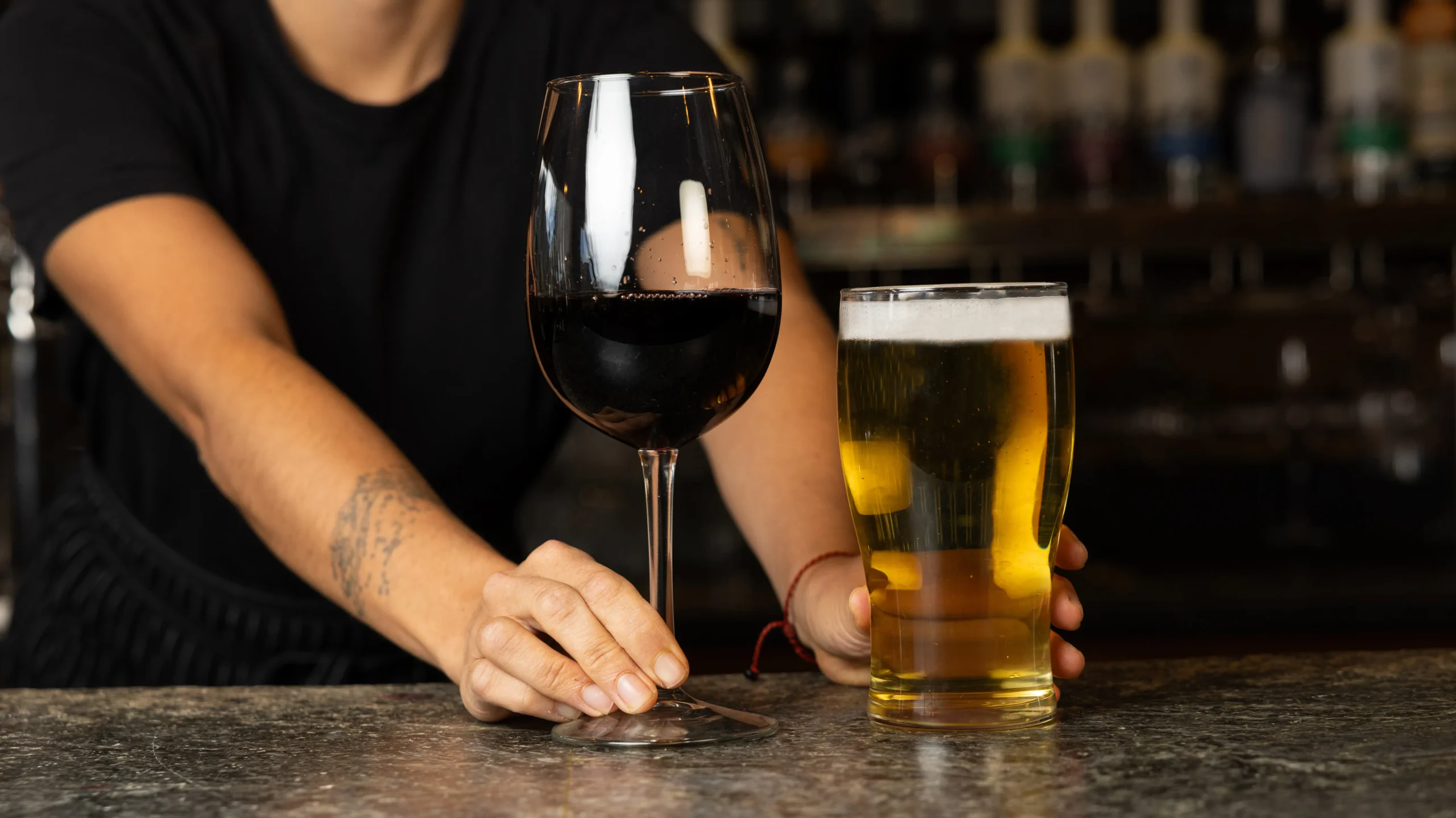 A Juniper bartender serves a glass of Canadian Okanagan Pinot Noir and a local beer