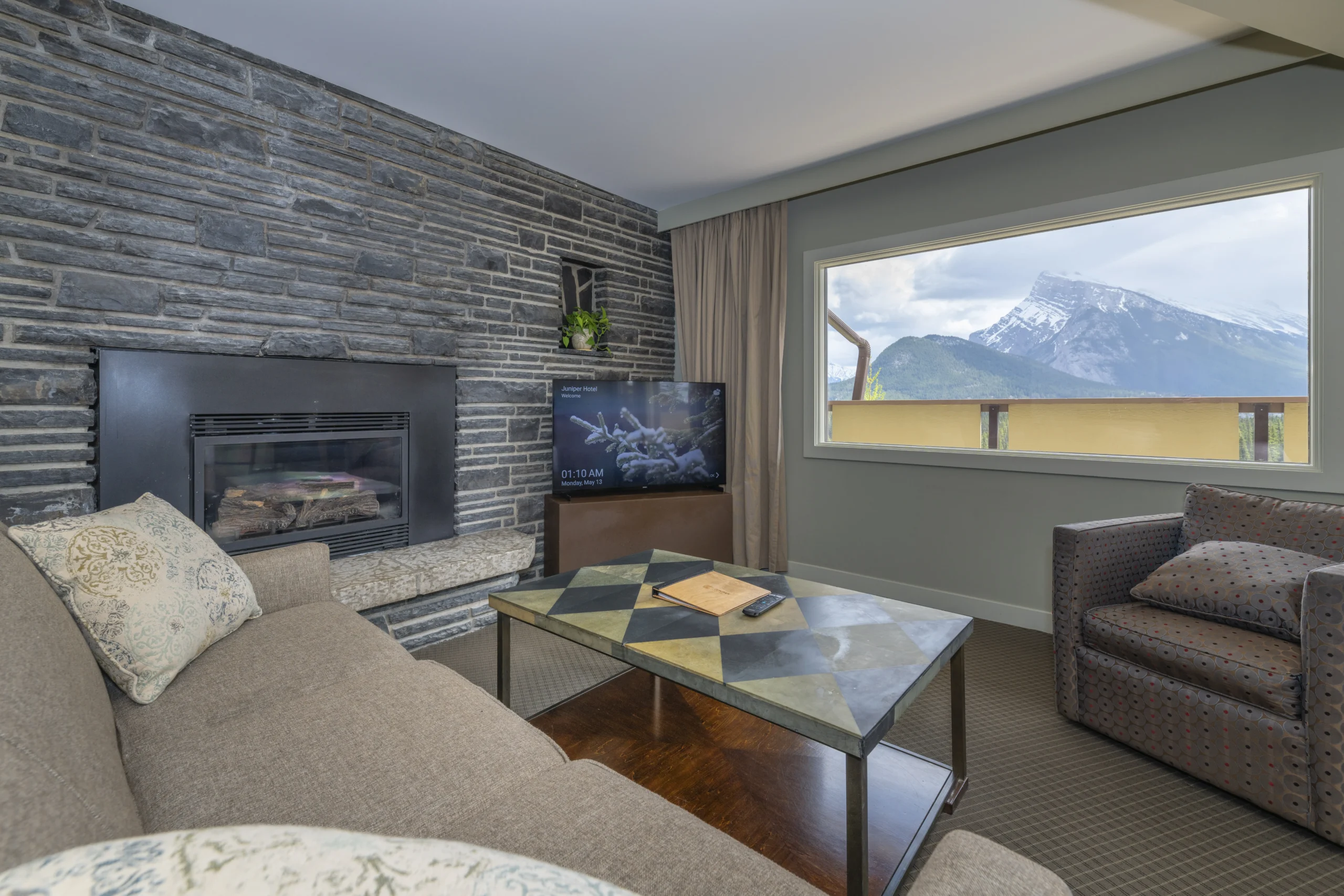The Juniper king suite layout includes a sofa, fireplace and views over Banff from the private balcony.