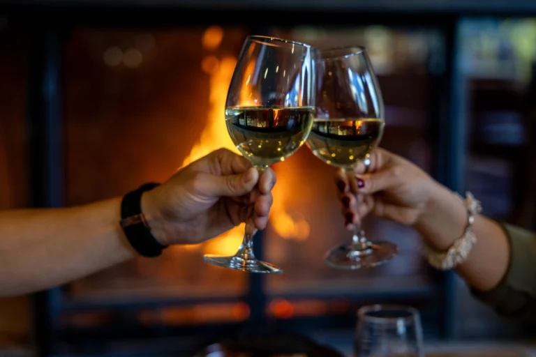 A couple enjoy wine by the fireplace in the Juniper Lounge