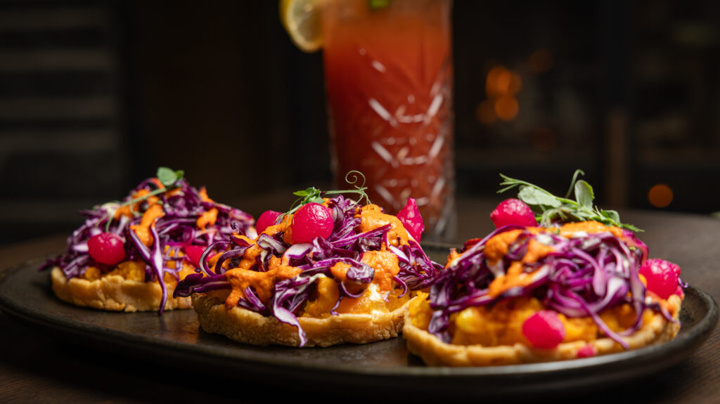Crispy fried corn sopes topped with Kabocha purée, piri piri sauce, and red cabbage, parsley cream